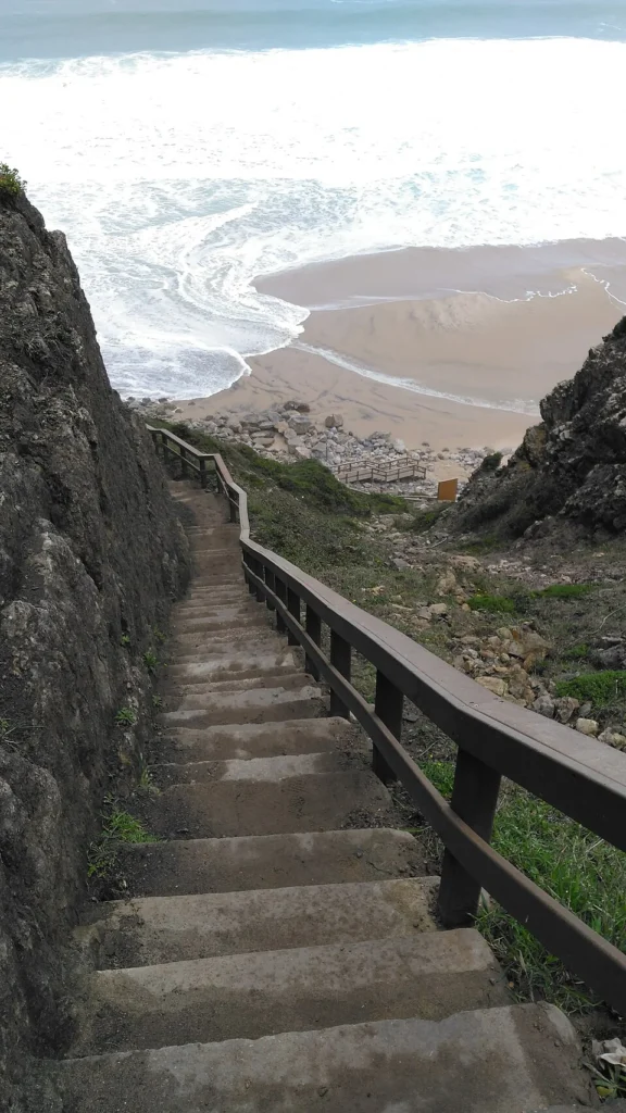 Escalinata entre los acantilados que desciende hacia Praia Grande, en la zona de las huellas de dinosaurio de Colares, Sintra.