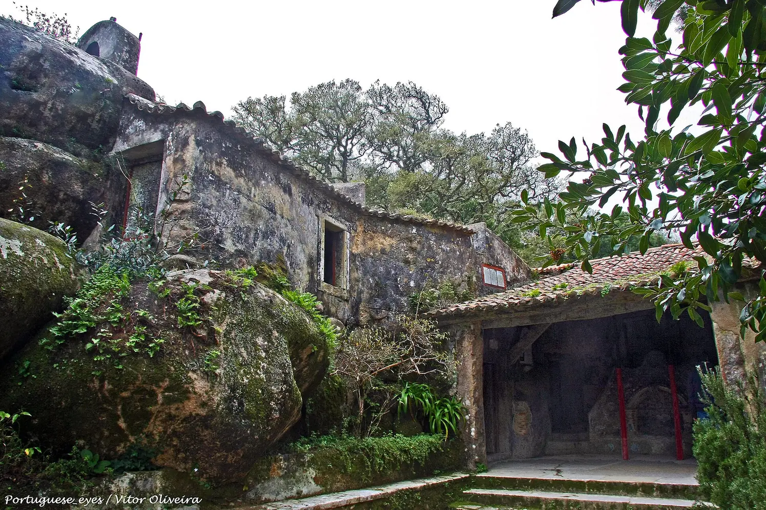 Edificio del Convento dos Capuchos integrado entre grandes rocas de granito y vegetación en la sierra de Sintra.