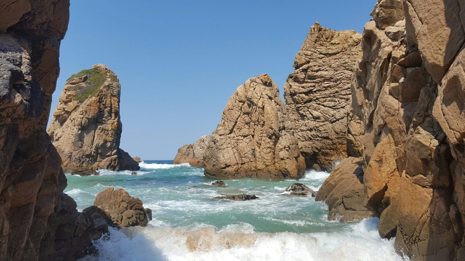 Oleaje entrando entre las grandes formaciones rocosas de Praia da Ursa, en la costa de Sintra.